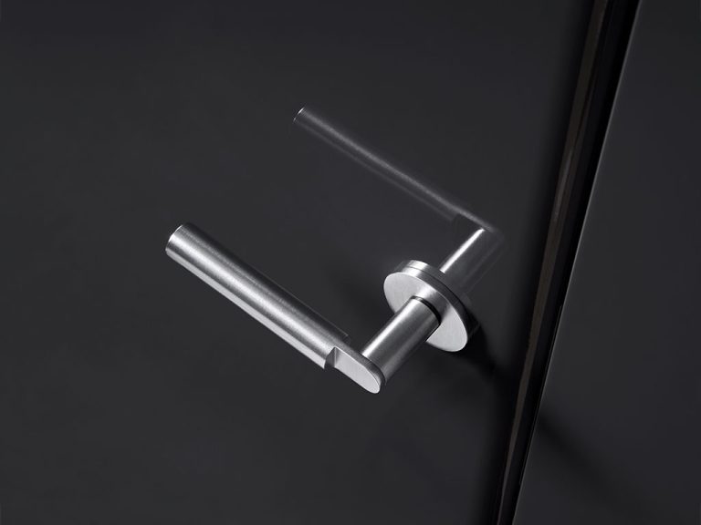 maniglia in acciao cromato dal design minimale montata su porta lucida grigio/nero